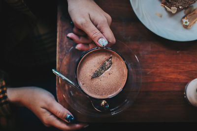 Midsection of man holding coffee cup on table