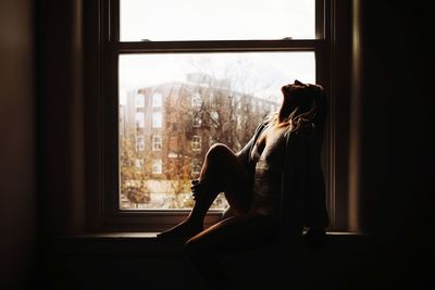 Woman looking through window at home