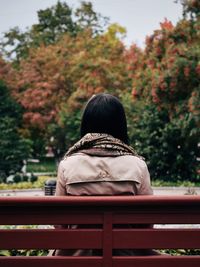 Rear view of woman sitting on park bench