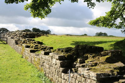 View of old ruin on field against cloudy sky