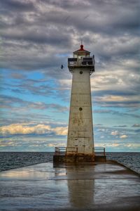 Lighthouse by sea against sky