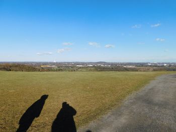 Low section of person on landscape against blue sky