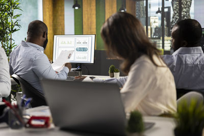 Rear view of people working at office