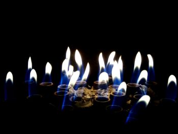 Close-up of illuminated candles in darkroom