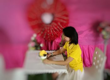 Full length of woman holding pink while standing on table