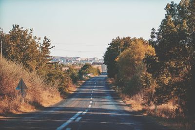 Road amidst trees against clear sky