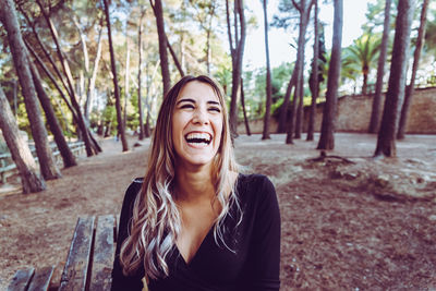 Portrait of smiling young woman against trees