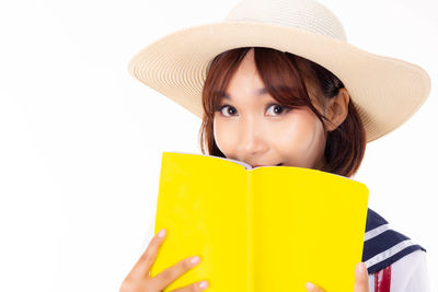 Portrait of young woman reading book against white background