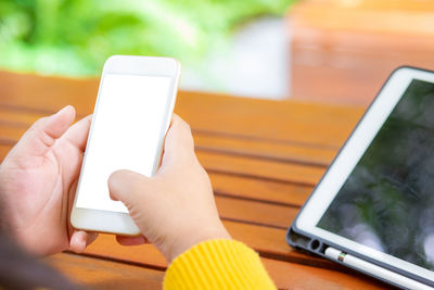 Close-up of hand holding mobile phone on table