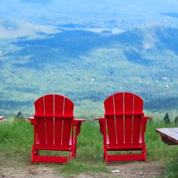 Red chairs on field by sea