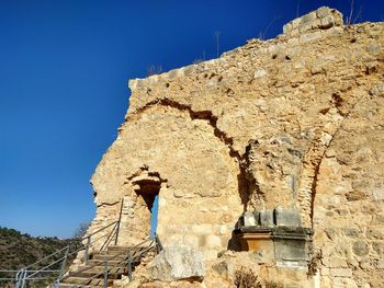 Low angle view of old building against clear blue sky