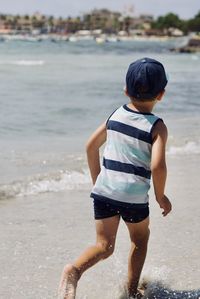 Rear view of boy standing at beach