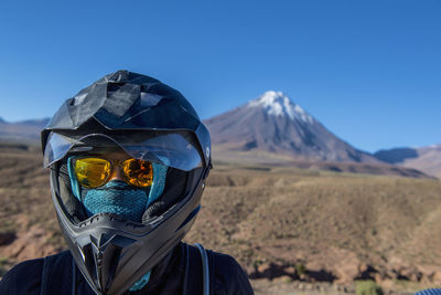 Woman with motorbike helmet, in front of the stratovolcano licancabur