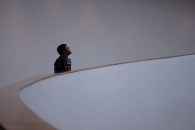 Side view of a woman sitting against wall