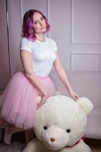 Full length of woman with pink toy sitting at home