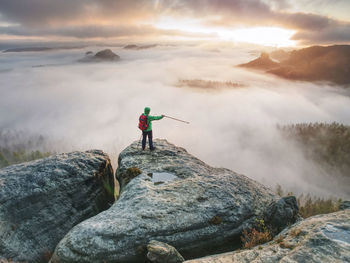 Extreme trail walker stop for relax above canyon full of  mist. body mirroring in water pool on top