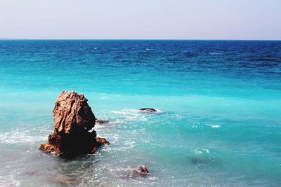 Scenic view of rocks in sea against clear sky