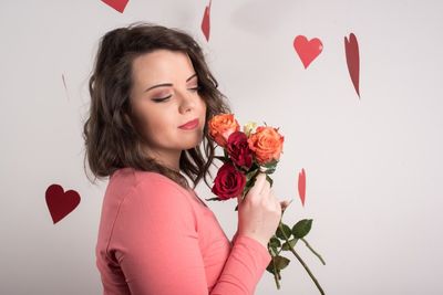 Young woman holding red rose in heart shape