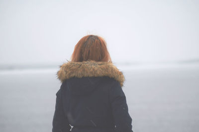 Woman in warm clothing at beach during winter