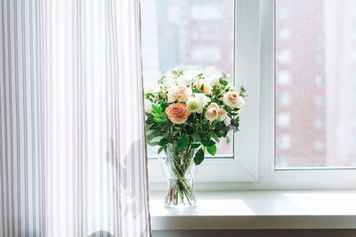 Flowers in vase against window at home