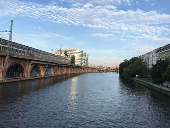 Bridge over river in city against sky