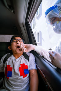 A young boy is taking a pcr swab test by drive thru lab.