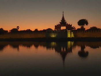 Scenic view of lake by building against sky during sunset