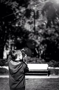 Rear view of boy standing against trees