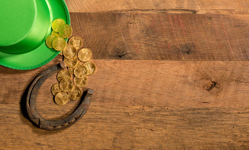 Directly above shot of coins with horseshoe and hat on wooden table