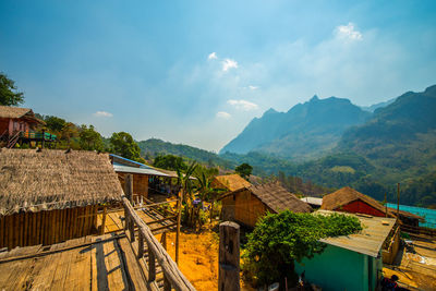 Houses by trees and buildings against sky