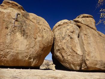 Low angle view of rock formation against clear blue sky