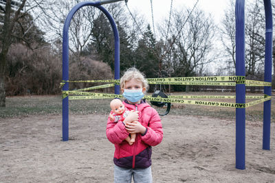 Portrait of cute girl wearing mask in park during winter