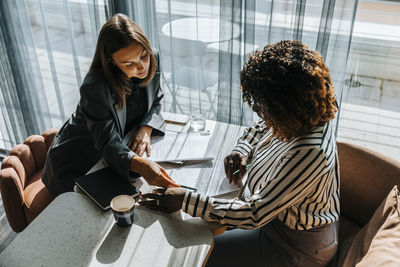 High angle view of female entrepreneur helping client while filling form