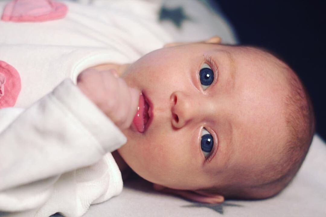 PORTRAIT OF CUTE BABY GIRL LYING ON HAND