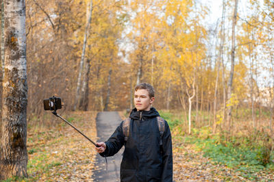 Boy vlogging in forest during autumn