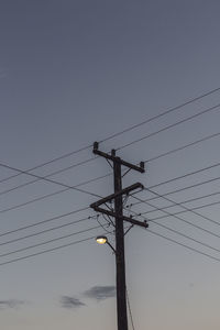 Low angle view of electricity pylon against clear sky