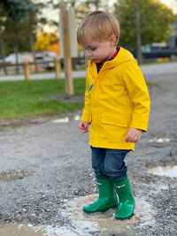 Cute boy standing in mud puddle 