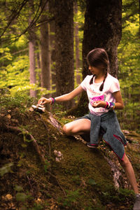Full length of girl on tree trunk in forest
