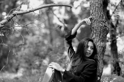 Portrait of woman with tree trunk in forest