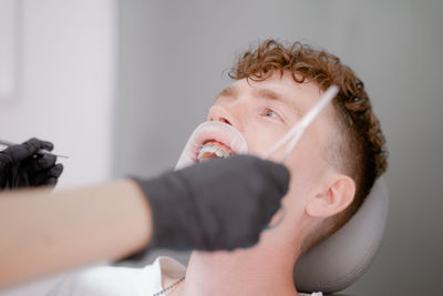 Young guy sitting happy in the orthodontist's chair while fixing braces