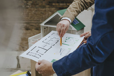 Hands of architects discussing over blueprint at construction site