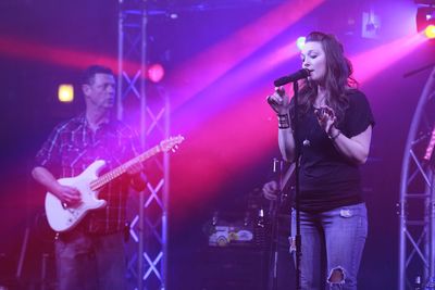 Woman singing while man playing guitar on stage