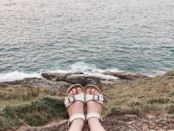 Low section of woman on hill by sea