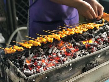 Close-up of man preparing food on barbecue grill