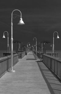 Lamp posts on empty pier against sky