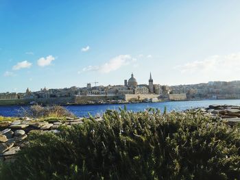 River and buildings in city against sky