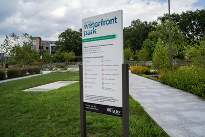 Information sign on grass against sky