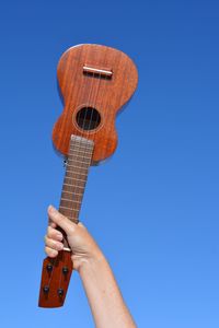 Cropped hand of woman holding violin against clear sky