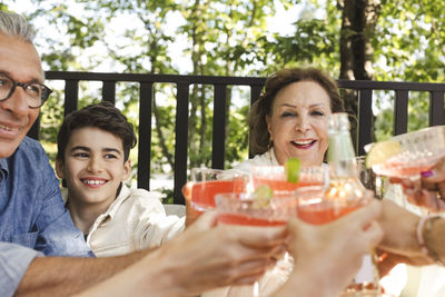 Happy family toasting drinks at patio in back yard