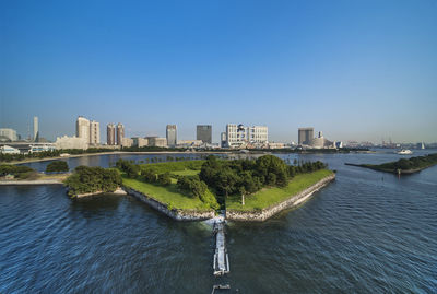 River amidst buildings in city against clear blue sky